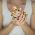 Beautiful woman hands with rainbow nail polish holding colorful swirl lollypops, funny cheerful