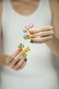 Beautiful woman hands with rainbow nail polish holding colorful swirl lollypops, funny cheerful