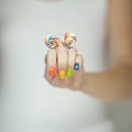 Beautiful woman hands with rainbow nail polish holding colorful swirl lollypops, funny cheerful