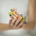 Beautiful woman hands with rainbow nail polish holding colorful swirl lollypops, funny cheerful