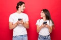 Beautiful woman and handsome man with smart phones isolated over red background Royalty Free Stock Photo