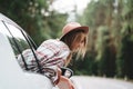 Beautiful woman in hat enjoying view of the road from the car window