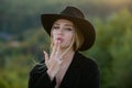 Beautiful woman in hat simulate shooting with and fingers. Fashion and beauty. Cowgirl in cowboy hat with finger gun.