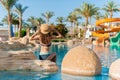 Beautiful Woman in hat sits on stone near swimming pool spa. Beautiful exotic hotel relax in Egypt. Blue water texture Royalty Free Stock Photo