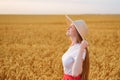 Beautiful woman in hat on wheat field background enjoying the sun. Weekend outsides