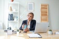 Beautiful woman having coffee at her desk in the office. Young woman drinking coffee at the workplace Royalty Free Stock Photo