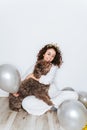 A beautiful woman having fun with her Spanish water dog in a New Year`s Eve. She is hugging her dog surrounded by balloons while