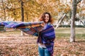 A beautiful woman having fun in the park in a wonderful autumnal day. She is smiling while covering herself with a big scarf.