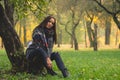 Beautiful woman having rest under tree. Lonely woman enjoying nature landscape in autumn. Royalty Free Stock Photo