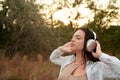 Beautiful woman in headphones dancing in the park and listening music, enjoying a summer rain. Royalty Free Stock Photo