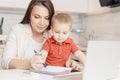 Beautiful woman helps son learn how to write alphabet letters. Online learning concept Royalty Free Stock Photo