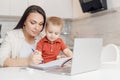 Beautiful woman helps son learn how to write alphabet letters. Online learning concept Royalty Free Stock Photo