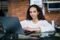 Beautiful young woman in her kitchen during her breakfast. She is using her laptop Royalty Free Stock Photo