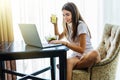 Young beautiful woman in her kitchen during her breakfast and using her laptop Royalty Free Stock Photo