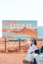 Beautiful woman on her trip by the car on the background of Welcome to Utah state border sign right in the Monument Royalty Free Stock Photo