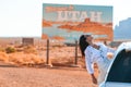 Beautiful woman on her trip by the car on the background of Welcome to Utah state border sign right in the Monument Royalty Free Stock Photo