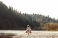 beautiful woman hipster walking on river beach in mountains,wearing hat and poncho, boho travel concept, space for text Royalty Free Stock Photo