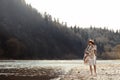 beautiful woman hipster walking on river beach in mountains,wearing hat and poncho, boho travel concept, space for text Royalty Free Stock Photo