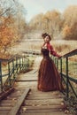 Beautiful woman in a historical dress descends a wooden staircase.