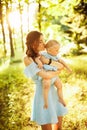 Beautiful woman hold little baby girl in caring arms, walking at the park, hugging, lovely mother kissing adorable