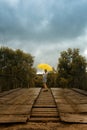 Beautiful woman hold yellow umbrella and walking on a old bridge in the countryside under rain Royalty Free Stock Photo