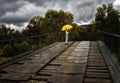 Beautiful woman hold yellow umbrella and walking on a old bridge in the countryside under rain Royalty Free Stock Photo