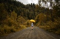 Beautiful woman hold yellow umbrella and walks on a country road under rain Royalty Free Stock Photo