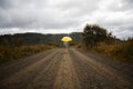 Beautiful woman hold yellow umbrella and walks on a country road under rain Royalty Free Stock Photo