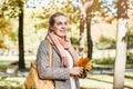 Beautiful woman holding autumn yellow and red maple leaf outdoors. Romantic girl in fall park Royalty Free Stock Photo