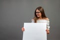 Beautiful woman holding a blank billboard on gray background - image