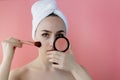 Beautiful woman holding blush brush to apply blush on cheeks on pink background Royalty Free Stock Photo