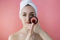 Beautiful woman holding blush brush to apply blush on cheeks on pink background Royalty Free Stock Photo