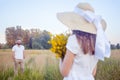 Beautiful woman holding bouquet of yellow flowers and looking at camera with her boyfriend on background. Royalty Free Stock Photo