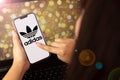 beautiful woman holding a cell phone with adidas logo