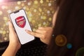 beautiful woman holding a cell phone with Arsenal logo Royalty Free Stock Photo