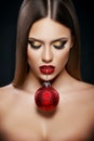 Beautiful woman holding a Christmas ornament with teeth over dark background Royalty Free Stock Photo