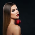 Beautiful woman holding a Christmas ornament with teeth over dark background Royalty Free Stock Photo