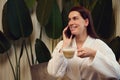 Beautiful woman holding a cup with cappuccino or coffee drink and talking on telephone while relaxing in the spa lounge after Royalty Free Stock Photo