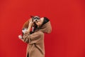 Beautiful woman holding cute biewer terrier dog in her arms and kissing, pet looking at camera, isolated on red background. Lady Royalty Free Stock Photo