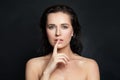 Beautiful woman holding finger near lips. Model with clear skin. Silence gesture Royalty Free Stock Photo