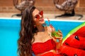 Beautiful woman Holding Glass coctail by watermelon float mattress swimming pool on villa resort. Sexy girl enjoy summer vacation Royalty Free Stock Photo