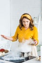 beautiful woman holding lid and looking at steam from pan on electric stove