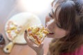 A beautiful woman is holding a piece of pizza and eating it. Pretty asian girl feels happy and enjoy eating the pizza. It looks so Royalty Free Stock Photo