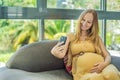 Beautiful woman holding pregnant belly and using phone, calling friends or family via video call Royalty Free Stock Photo