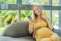 Beautiful woman holding pregnant belly and using phone, calling friends or family via video call Royalty Free Stock Photo