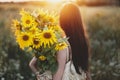 Beautiful woman holding sunflowers bouquet close up in warm sunset light in summer meadow. Tranquil atmospheric moment in