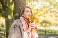 Beautiful woman holding yellow maple leaf outdoors. Romantic girl dreams in autumn fall park Royalty Free Stock Photo