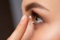 Beautiful woman holds contact lens on her finger. Eye care and the choice between the means to improve vision Royalty Free Stock Photo