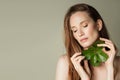 Beautiful woman holds a green leaves in her hands. Cleanliness and care