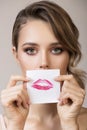 Beautiful woman holds the imprint of her kiss on paper near her face Royalty Free Stock Photo